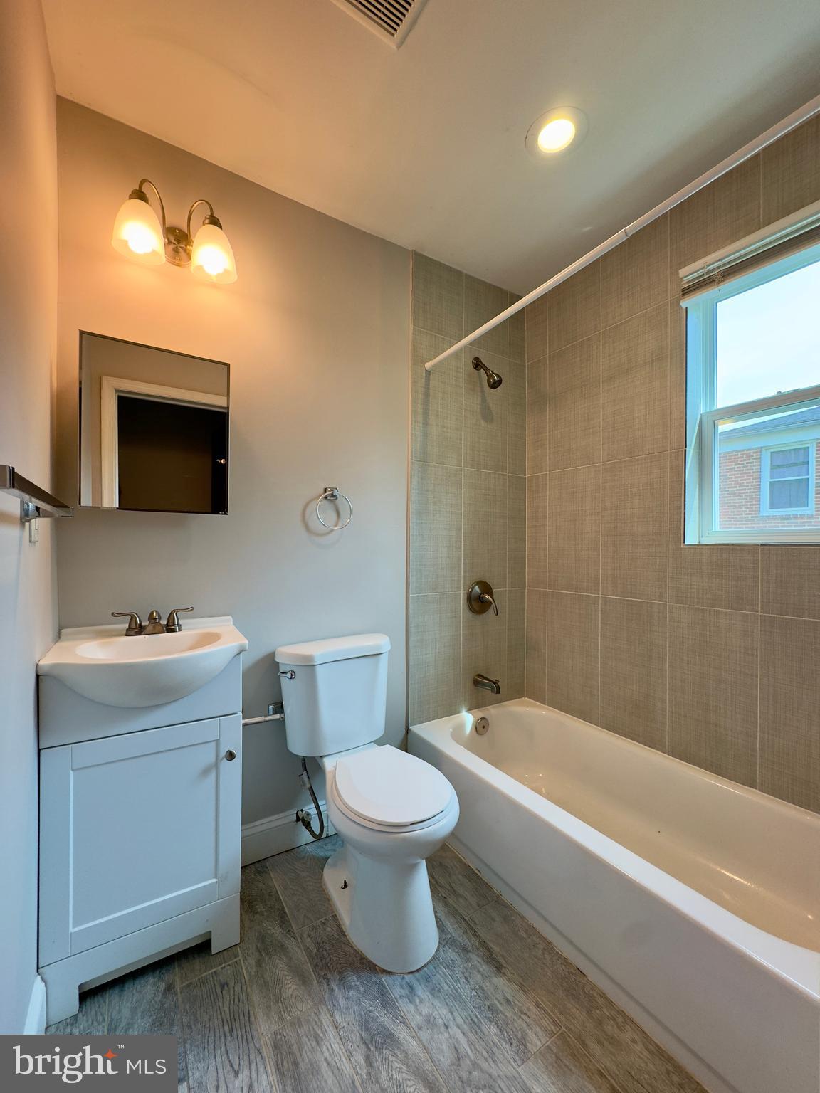 1111 Gleneagle Road, Unit 2 Baltimore, MD 21239 - Photo 8 of 11 a bathroom with a toilet sink a mirror a bathtub and shower