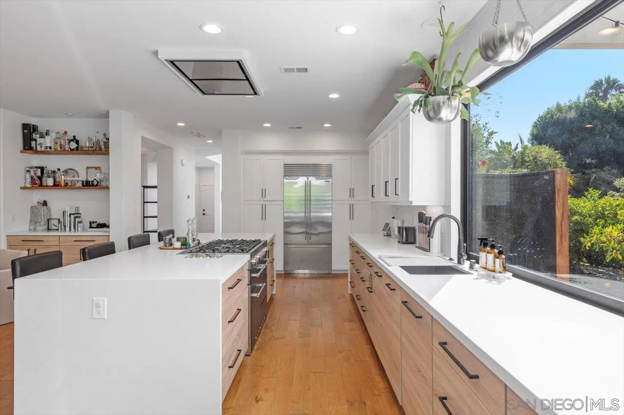 219 Jacob Lane Encinitas, CA 92024 - Photo 15 of 46 a large white kitchen with a large window a sink and stainless steel appliances