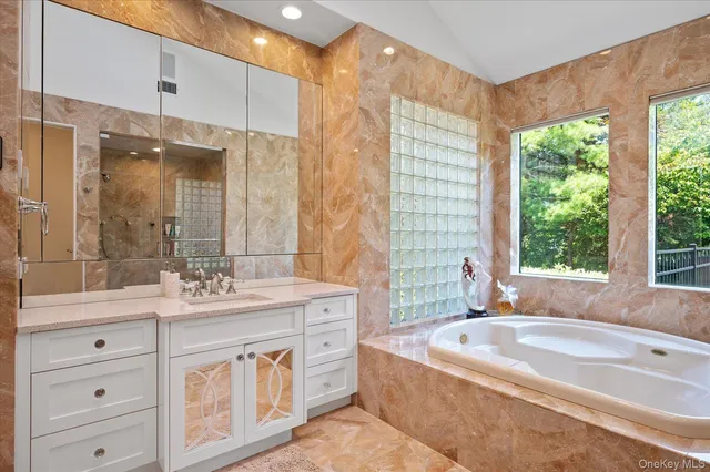 a bathroom with a granite countertop tub sink and mirror