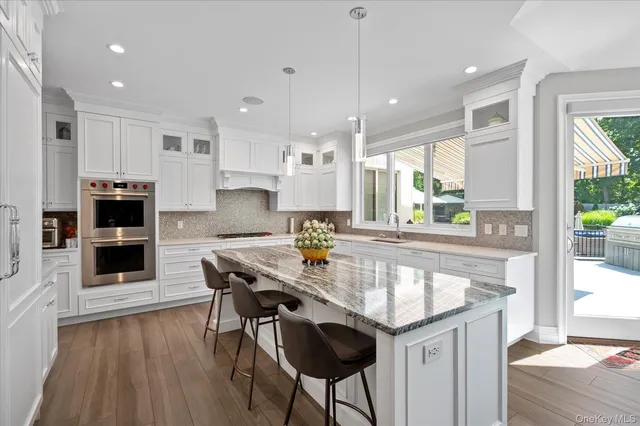 a kitchen with stainless steel appliances granite countertop a stove top oven a sink dishwasher a dining table and chairs with wooden floor