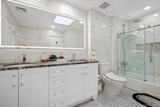 a bathroom with a granite countertop sink a toilet a mirror and shower