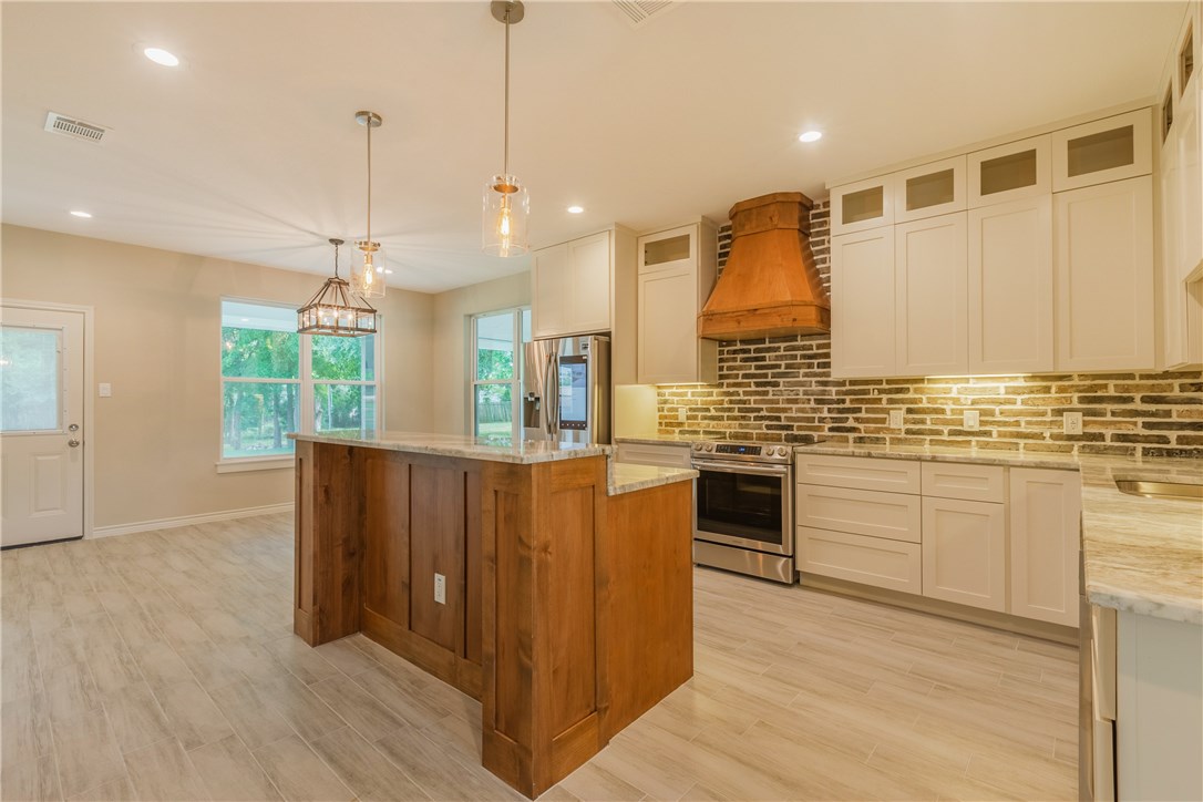 a kitchen with stainless steel appliances granite countertop a stove a sink dishwasher and a refrigerator with wooden floor