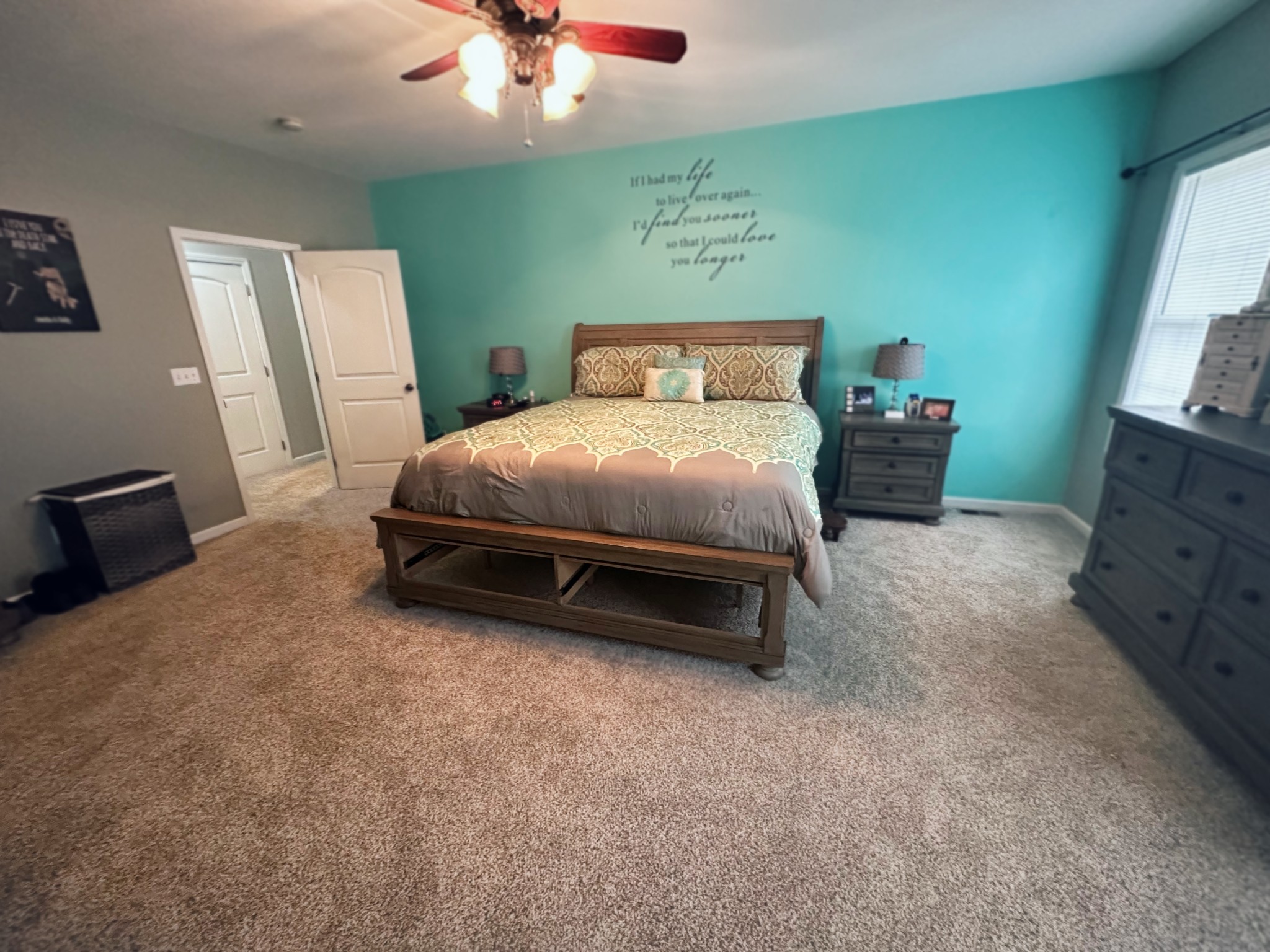 a spacious bedroom with a bed and a flat tv screen on dresser