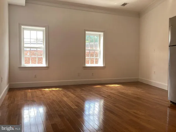 an empty room with wooden floor and windows