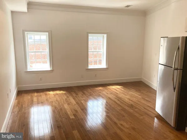 a view of an empty room with wooden floor and a window