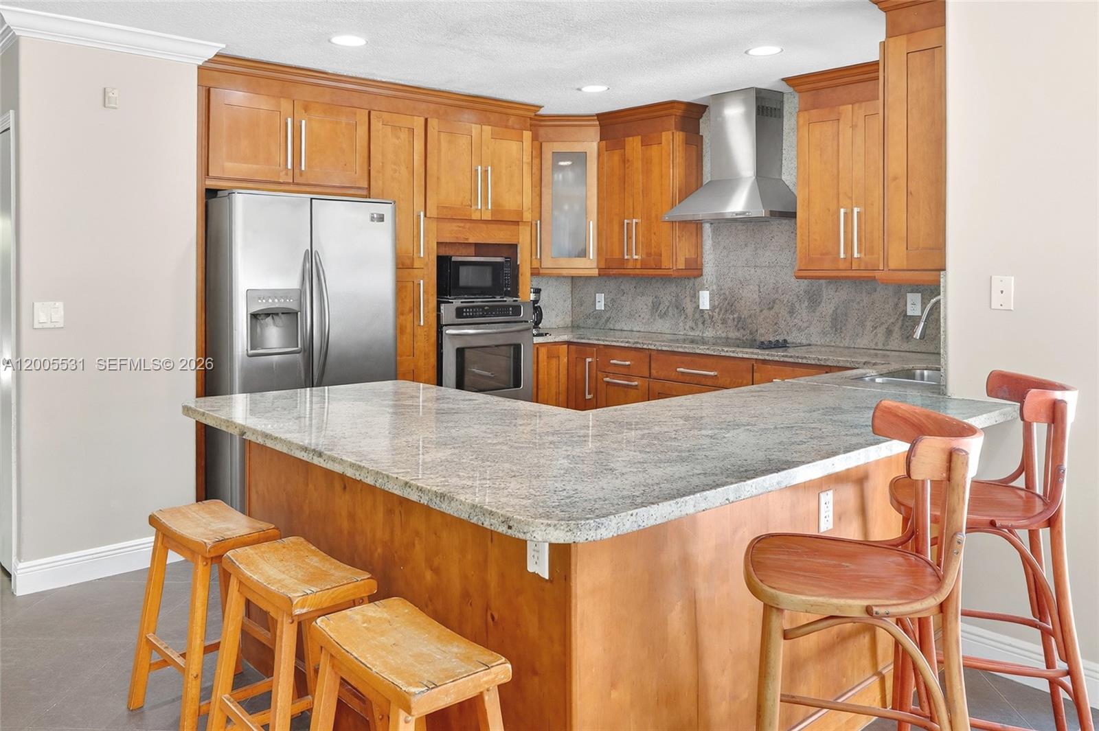 5310 Southwest 72nd Street Miami, FL 33143 - Photo 10 of 20 a kitchen with stainless steel appliances granite countertop a sink a stove a refrigerator a dining table and chairs with wooden floor
