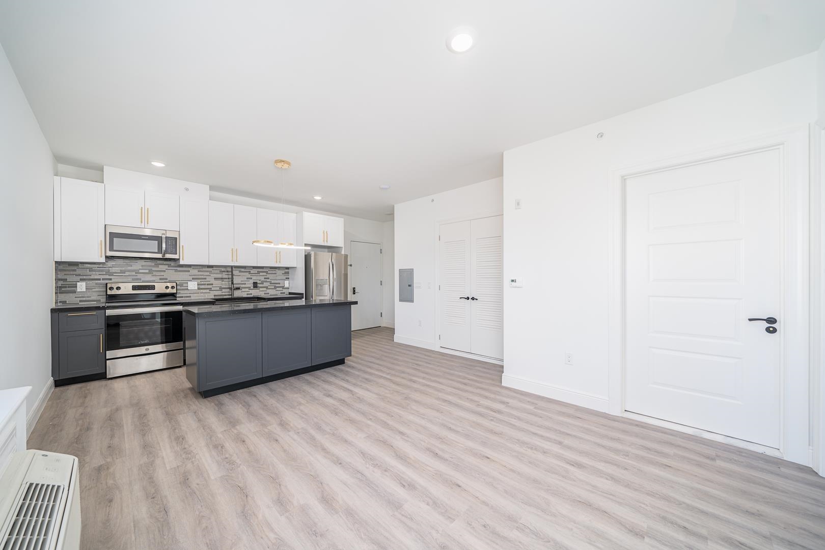 a large kitchen with a wooden floor and stainless steel appliances