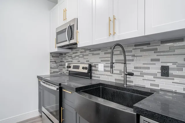 a kitchen with granite countertop a sink stainless steel appliances and cabinets
