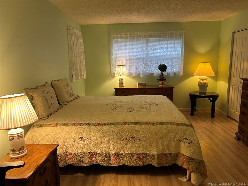 2950 Southeast Ocean Boulevard, Unit 1323 Stuart, FL 34996 - Photo 9 of 19 a bed sitting in a bedroom next to a window with wooden floor