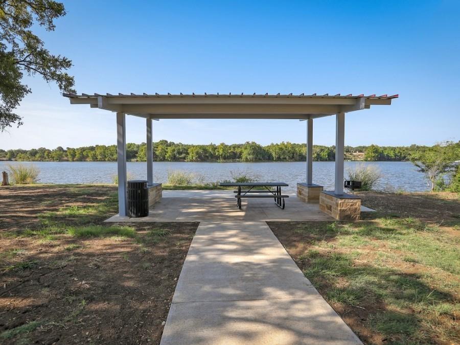 1836 Turtle Bay Loop Leander, TX 78641 - Photo 29 of 32 Waterfront pavilion featuring a concrete patio, metal pergola structure, and stone-clad bases