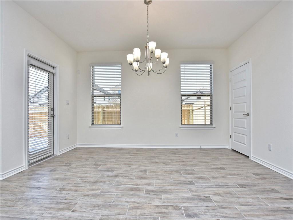 1836 Turtle Bay Loop Leander, TX 78641 - Photo 9 of 32 Spacious room featuring light-toned wood-finish tile flooring, a contemporary chandelier, two windows with blinds, a glass-paneled door, and white baseboards