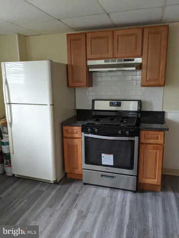 a kitchen with granite countertop a refrigerator stove and cabinets
