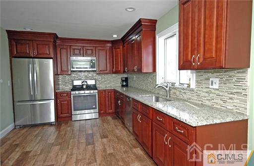 340 Bound Brook Road Middlesex, NJ 08846 - Photo 21 of 22 a kitchen with stainless steel appliances granite countertop a refrigerator a sink dishwasher and wooden cabinets with wooden floor