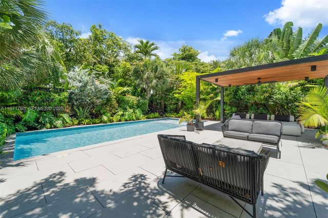 a view of backyard with seating space and trees in the background