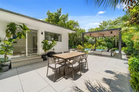 a patio with table and chairs and potted plants