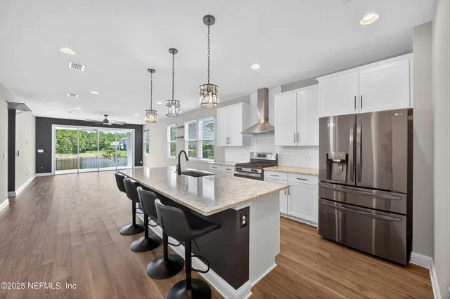 a kitchen with stainless steel appliances a dining table chairs a refrigerator and wooden floor