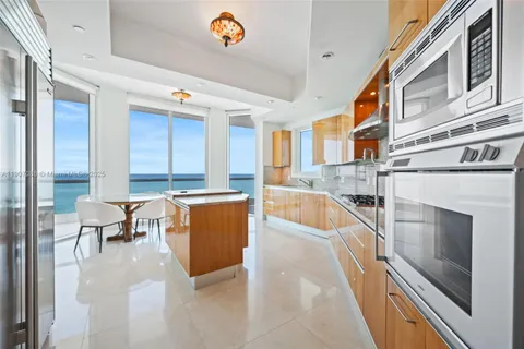 a large white kitchen with granite countertop a sink and a stove