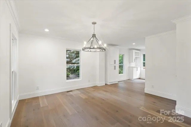 a view of a room with wooden floor ceiling fan and windows