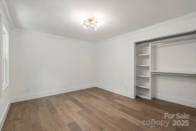 an empty room with wooden floor closet and windows