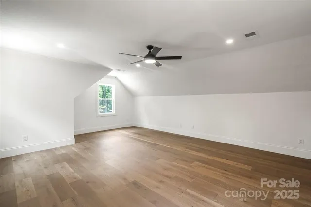 an empty room with wooden floor and ceiling fan