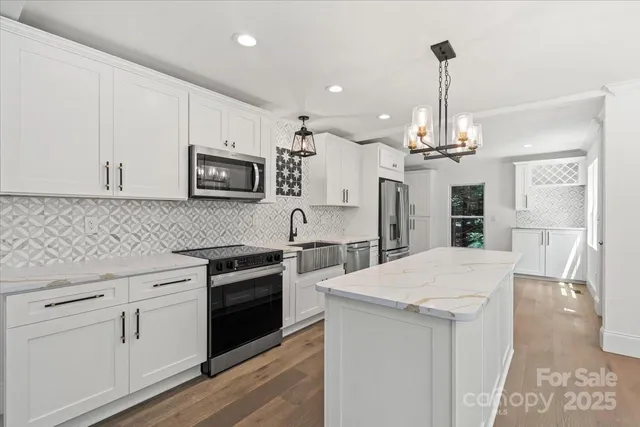 a kitchen with stainless steel appliances kitchen island granite countertop a stove sink and microwave