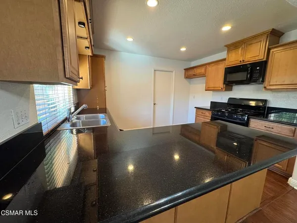 a kitchen with stainless steel appliances granite countertop a sink a stove top oven a counter top space and cabinets