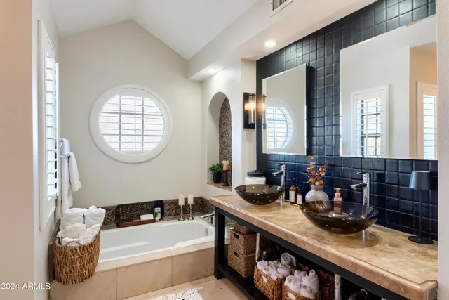 a bathroom with a granite countertop sink a mirror and a bathtub