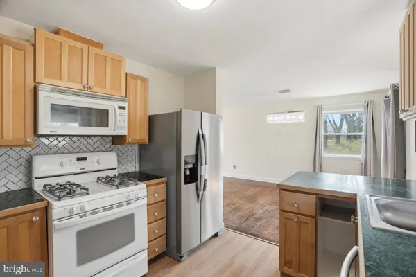a kitchen with granite countertop a stove microwave and refrigerator