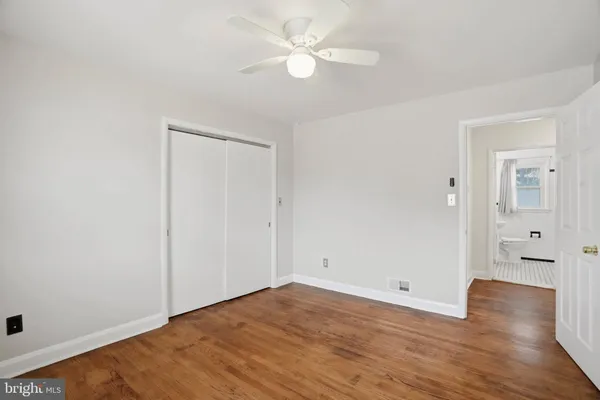 an empty room with wooden floor and a ceiling fan