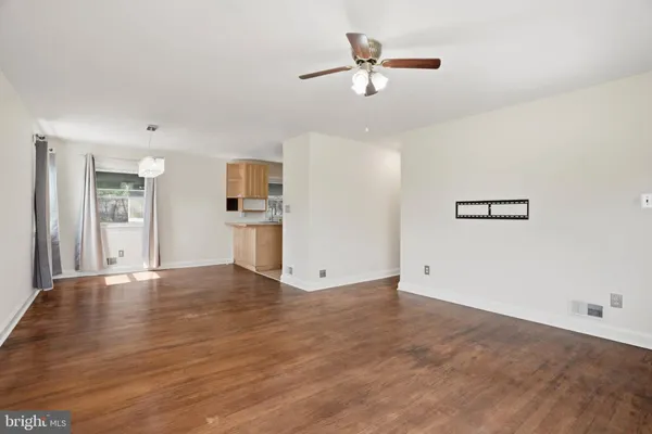 a view of empty room with wooden floor and ceiling fan