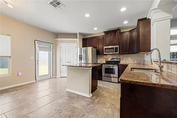 a kitchen with stainless steel appliances granite countertop a stove a sink and a microwave
