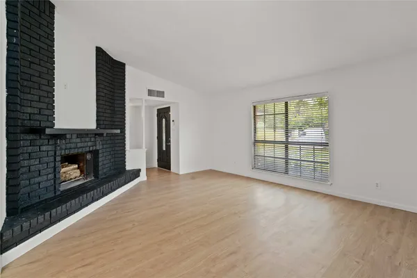an empty room with windows and fireplace