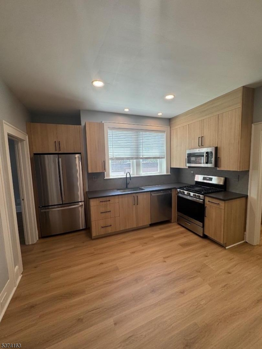 a kitchen with granite countertop a refrigerator and wooden floors