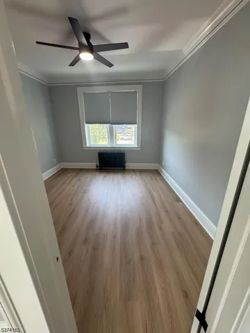 a view of a livingroom with wooden floor a ceiling fan and window