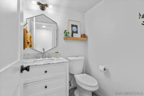 a bathroom with a granite countertop toilet sink and mirror