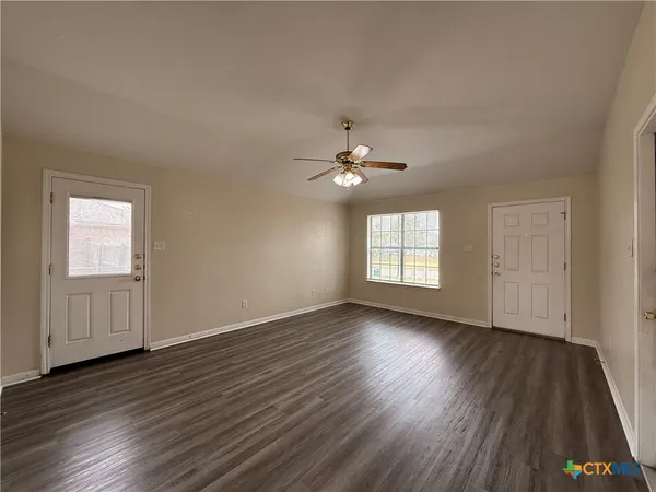 a view of an empty room with wooden floor and a window