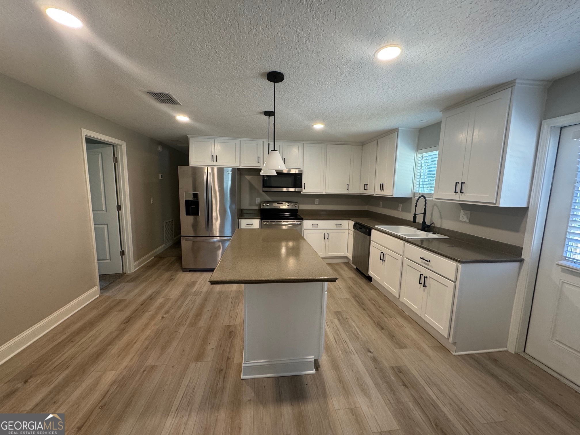 2199 Tom Crawford Road Hilliard, FL 32046 - Photo 7 of 18 a large kitchen with stainless steel appliances granite countertop a lot of counter space and wooden floors