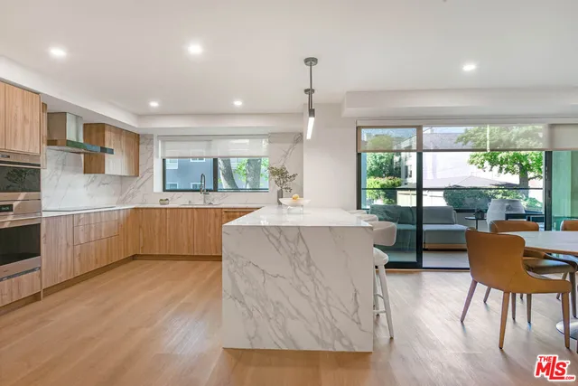 a kitchen with stainless steel appliances kitchen island granite countertop a refrigerator and a sink