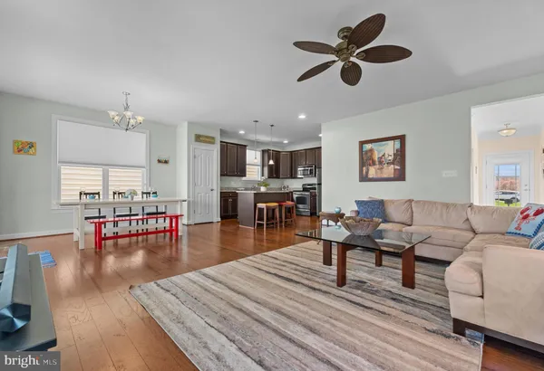 a living room with furniture and kitchen view with wooden floor