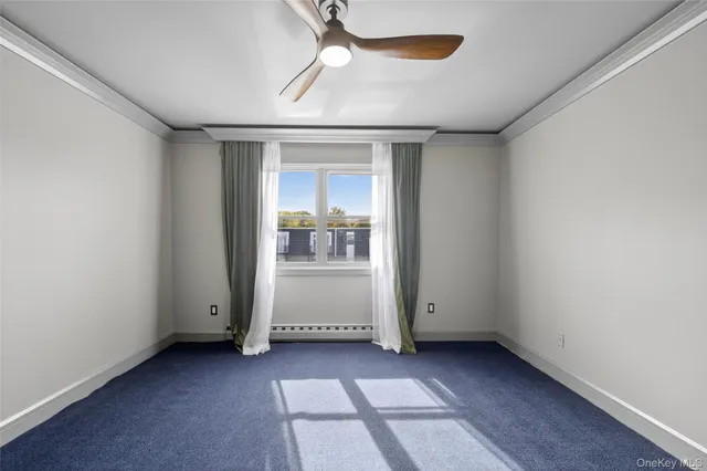 an empty room with chandelier fan and windows