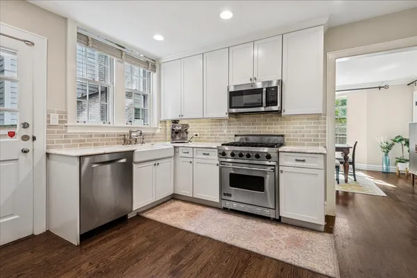 a kitchen with stainless steel appliances white cabinets a sink and a stove