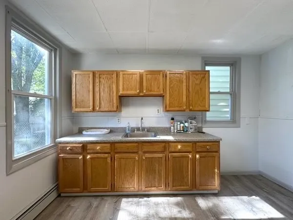 an empty room with wooden floor fan and windows