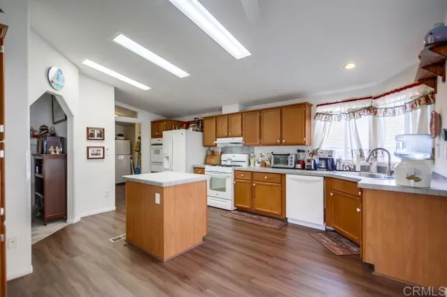 a kitchen with stainless steel appliances granite countertop wooden floors and white cabinets