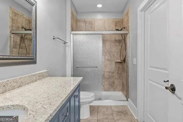 a bathroom with a granite countertop sink toilet and shower