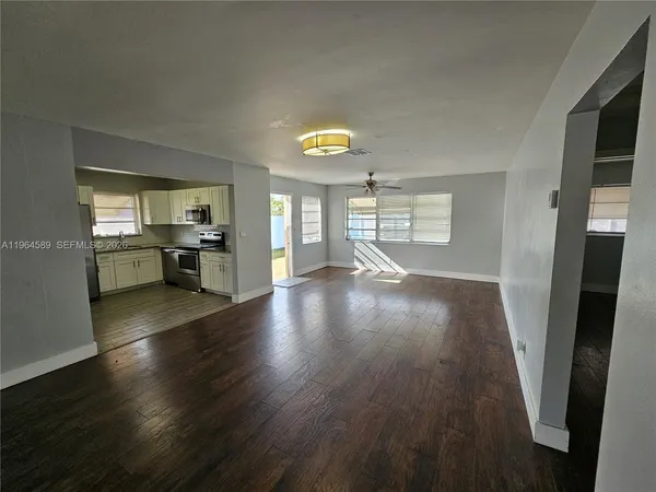 a view of empty room with kitchen and window