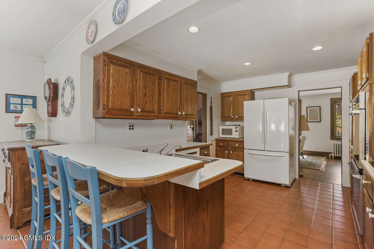242 Taconic Road Greenwich, CT 06831 - Photo 17 of 37 a kitchen that has a refrigerator a stove a sink and a dining table with wooden cabinet