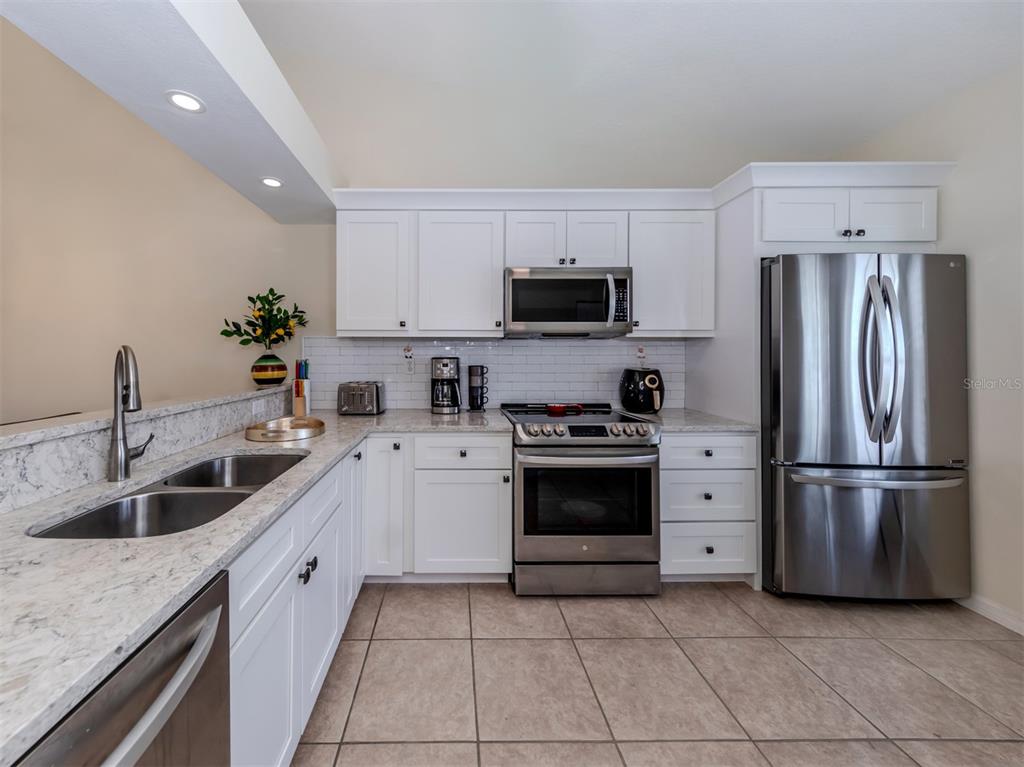 901 Addington Court, Unit 203 Venice, FL 34293 - Photo 7 of 61 a kitchen with stainless steel appliances granite countertop a refrigerator sink and stove
