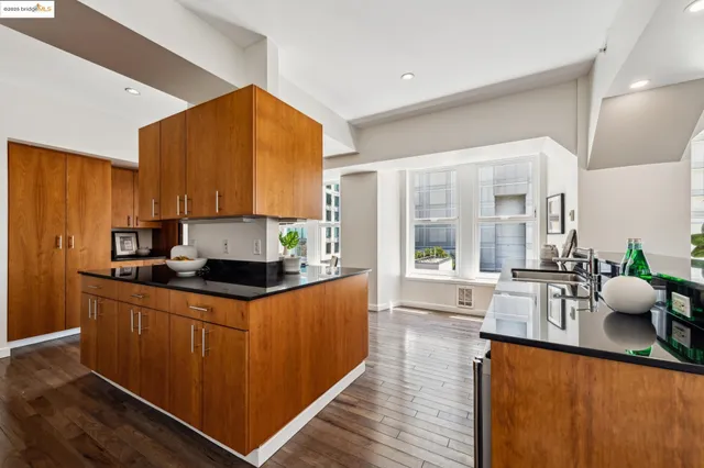 a kitchen with stainless steel appliances granite countertop a refrigerator a stove a sink a dining table and chairs with wooden floor