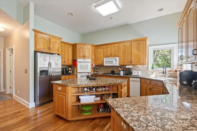 a kitchen with stainless steel appliances granite countertop sink stove top oven and refrigerator