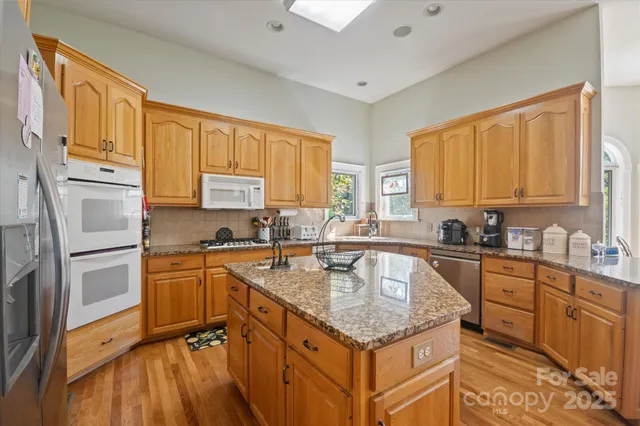 a kitchen with stainless steel appliances granite countertop a sink stove refrigerator and cabinets